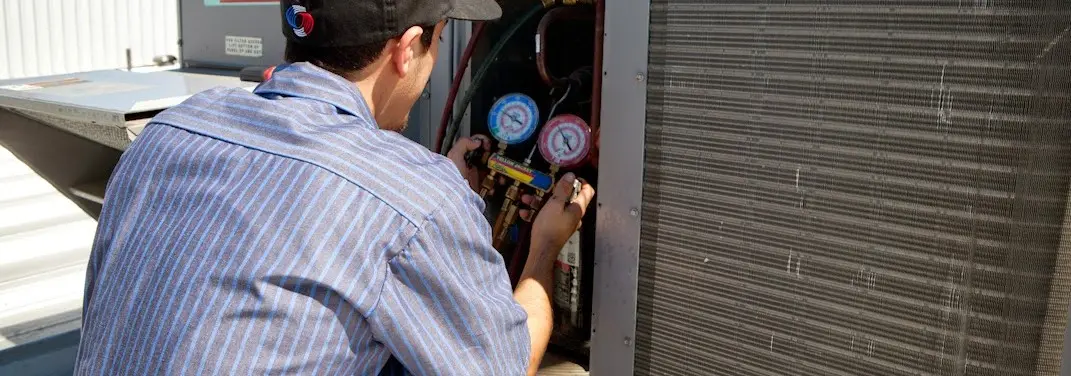 HVAC technician servicing a condenser unit in Tracyton